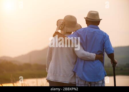 Ein glückliches älteres Paar asiatischer alter Mann und Frau, die im Sommer in der Nähe von Berg und See während Sonnenaufgang oder Sonnenuntergang stehen. Senior Healthcare and Relationship Stockfoto