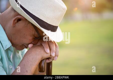 Nahaufnahme trauriger älterer asiatischer alter Mann, der im Park sitzend verloren ging. Konzept für das Gesundheitswesen. Stockfoto