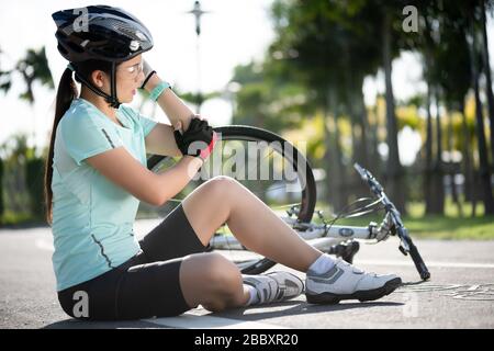 Radverletzungen. Junge Radfahrerin ist beim Radsport vom Straßenrad gefallen. Fahrradunfall, verletztes Knie. Stockfoto