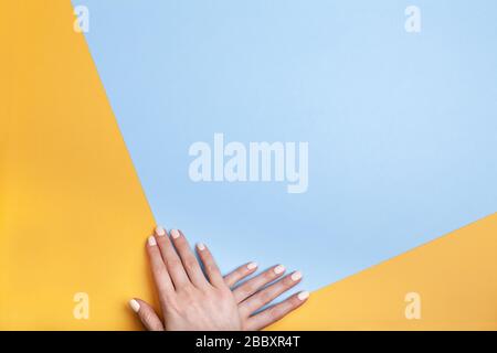 Schöne weibliche Hände mit klassischer Mattenmaniküre auf blaugelbem Hintergrund. Platz für Ihren Text. Stockfoto