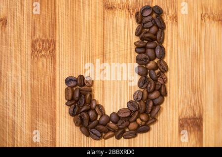 Buchstaben J aus gerösteten Kaffeebohnen, 3D-Rendering auf Holztischhintergrund Stockfoto