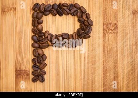 Buchstaben P aus gerösteten Kaffeebohnen, 3D-Rendering auf Holztischhintergrund Stockfoto