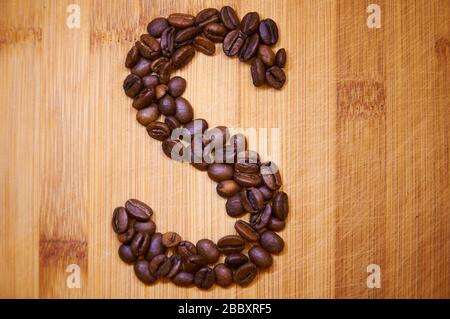 Buchstaben S aus gerösteten Kaffeebohnen, 3D-Rendering auf Holztischhintergrund Stockfoto