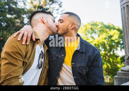 Porträt des fröhlichen schwulen Paares, das Zeit zusammen verbringt und im Park küsst. LGBT und Love Konzept. Stockfoto