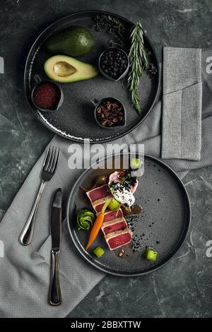 Appetitlicher, leicht gebratener Thunfisch mit gegrilltem Gemüse aus nächster Nähe, traditionelle italienische Küche, grauer Hintergrund, ein Gericht vom Küchenchef, Kopierer, Essen Stockfoto