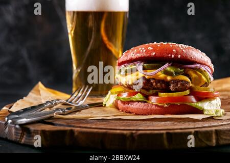 Saftige Burger, pommes Frites, Saucen und ein Glas kaltes Bier auf dunklem Holzhintergrund. Kopierraum, Fast Food Set, Food Foto Stockfoto