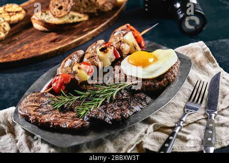 Grillplatte auf einem Teller mit gegrilltem Gemüse, gegrilltem Fleisch. Food Foto, dunkler Hintergrund Stockfoto