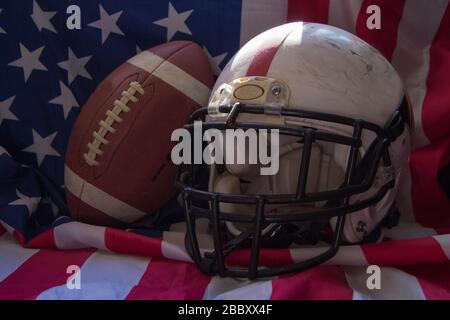 American Football Ball und Helm mit Flagge der Vereinigten Staaten im Hintergrund Stockfoto