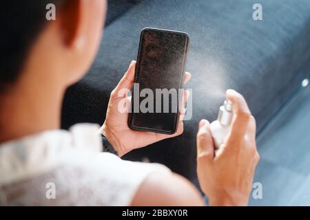 Frau - Reinigen Und Desinfizieren Des Mobiltelefons Gegen Viren Stockfoto