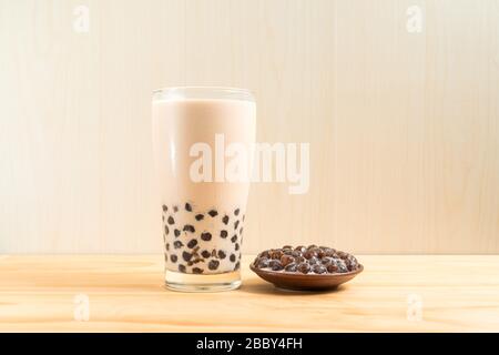 Ein Glas Tasse pearl Milch Tee (auch genannt Bubble Tea) und eine Platte von Tapioka Kugel auf Holz- Hintergrund. Pearl Milch Kaffee ist die repräsentativste dri Stockfoto