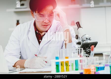 Wissenschaftler hart arbeitende Kopfschmerzerkrankung während langjähriger Arbeit im medizinischen Labortest Stockfoto