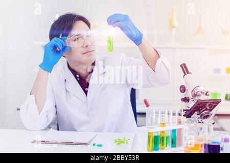 Wissenschaftler, stolz und erfolgreich betrachtet, um neuen Medikamentenextrakt aus dem grünen Blatt im Labor für Biowissenschaften zu entdecken. Stockfoto