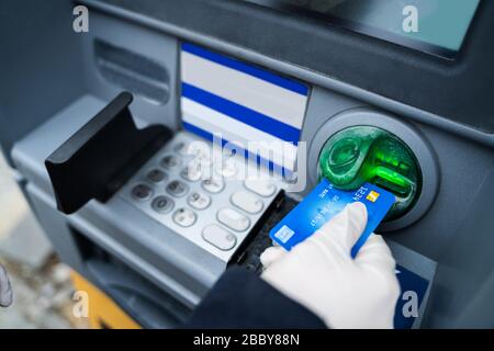 Tragen von Handschuhen beim Einsatz von ATM zum Schutz vor Coronavirus Infektionen Stockfoto