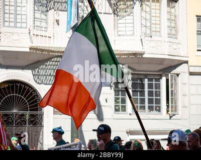 Menschen in der Parade, die irische Flagge auf der Straße marschieren halten Stockfoto
