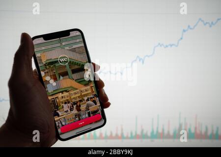 WeWork App und Logo auf dem Telefon mit weißem Finanz-Aktiendiagramm mit einem Preisanstieg im Hintergrund Stockfoto