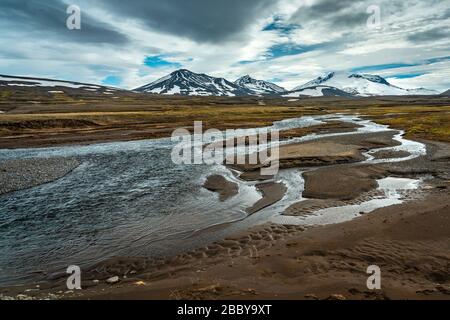Schöne isländische Landschaft mit Fluss und schneebedeckten Bergen im Hintergrund Stockfoto