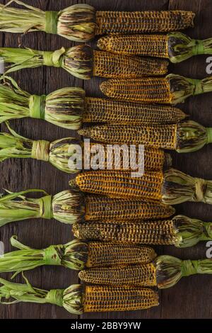 cob, Sahnesauce, dunkler Hintergrund, vegetarisches Essen, saure Sahne, Maiskolben, flaches Lay Stockfoto