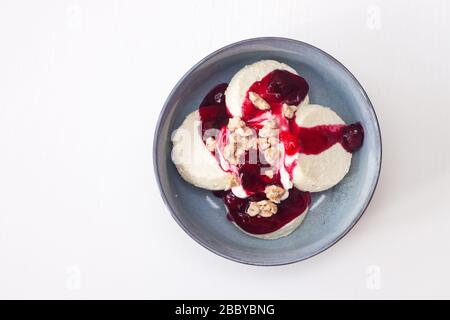 Käsekäse oder Pfannkuchen mit Kirschsoße und gehackten Nüssen auf weißem Hintergrund. Isoliert. Stockfoto