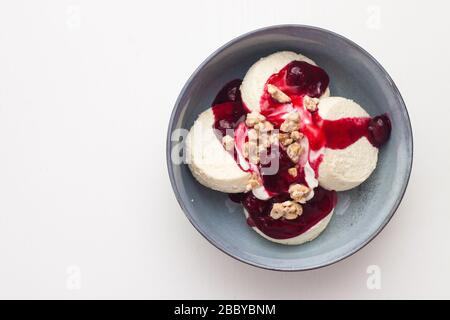 Käsekäse oder Pfannkuchen mit Kirschsoße und gehackten Nüssen auf weißem Hintergrund. Isoliert. Stockfoto