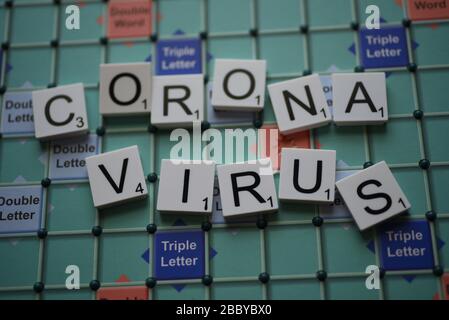 Coronavirus buchstabierte auf einem Scrabble Board. Konzeptbild für redaktionelle Kovid-19-bezogene Geschichten. Mit selektivem Fokus. Stockfoto