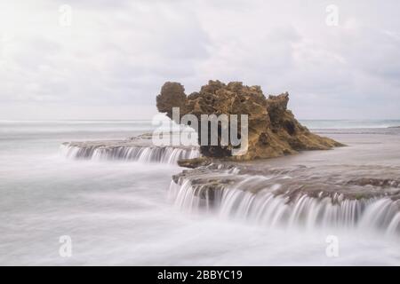 Ein entsäumter Drachenkopffelsen in Rye mit seidenem, glattem Wasser, das aus den umliegenden Felsen kaskadiert wird Stockfoto