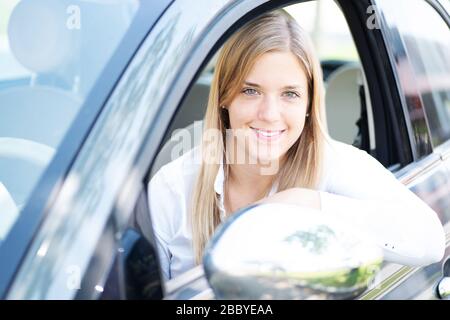 Personable junge Frau mit nettem Lachen sitzt in einem neuen Auto Stockfoto