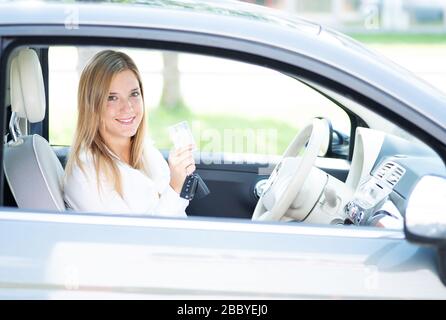 Die junge Frau im Auto zeigt stolz ihren Führerschein Stockfoto