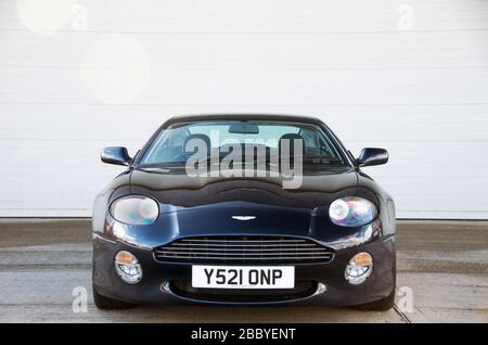Das dunkelblaue Aston Martin DB7 Vantage Coupé hat vorne mit interessanten Reflexen auf der Motorhaube gedreht. Stockfoto