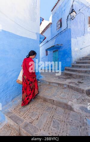 Chefchaouen, Marokko: Eine Frau in Rot, die in der Medina spaziert Stockfoto