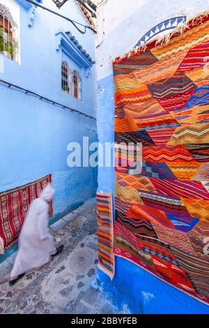 Chefchaouen, Marokko: Mann in einem weißen Djellaba, der in der Medina spazieren geht Stockfoto