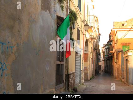 Italienische Flagge in der Nähe der Häuser in einer Gasse in der Altstadt. Ermutigen Sie alle Menschen, diese Quarantänezeit für Kovid 19 zu überschreiten. Stockfoto