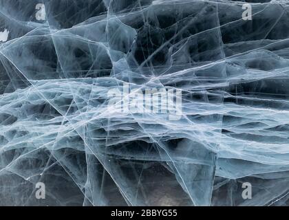 Das graue Eis des Baikalsee in vielen weißen Rissen in der Nähe der grafischen Hintergrundquelle. Stockfoto