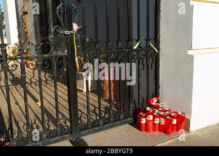 Ein paar Kerzen vor dem verschlossenen Tor des städtischen Friedhofs und eine Blume, die an die Kette gebunden ist. Verschlossener heiliges Ort für Regierungskund - 1 Stockfoto