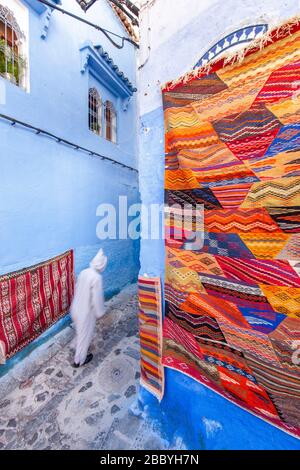 Chefchaouen, Marokko: Mann in einem weißen Djellaba, der in der Medina spazieren geht Stockfoto