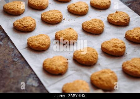 Frisch gebackene herzförmige Plätzchen auf Pergamentpapier. Stockfoto