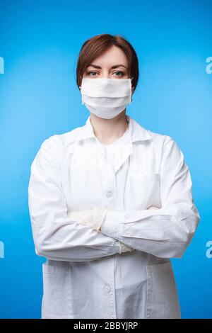 Porträt des professionellen weiblichen Arztes in weißer Uniform und Schutzmaske, die isoliert posiert Stockfoto