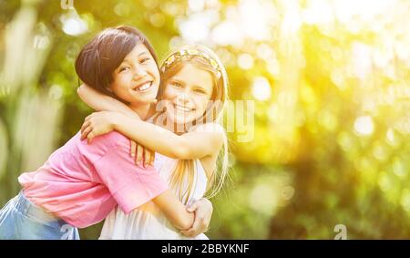 Zwei Mädchen als beste Freunde umarmen sich im Sommer in der Natur Stockfoto