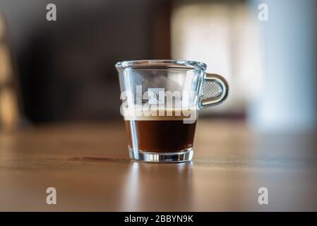 Transparentes Nespresso-Glas Kaffee auf einem Tisch mit verschwommenem Hintergrund Stockfoto