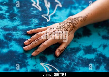 Henna Kunst-Tattoo auf weiblicher Hand mit blauem Hintergrund Stockfoto