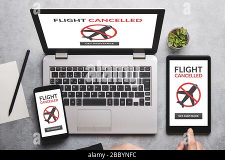 Flight Cancelled Concept auf Laptop, Tablet und Smartphone-Bildschirm über grauem Tisch. Flaches Lay Stockfoto