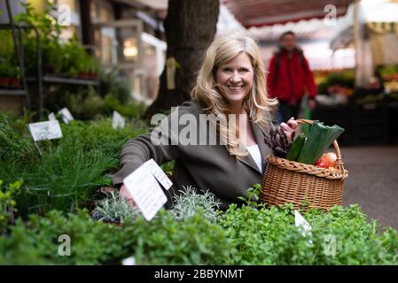 Eine attraktive Frau mittleren Alters kauft frische Produkte auf dem Markt Stockfoto