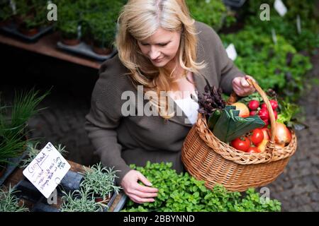 Eine attraktive Frau mittleren Alters kauft frische Produkte auf dem Markt Stockfoto