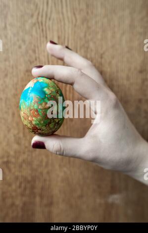 Ein hart gekochtes, schön dekoriertes Osterei in der Hand einer Frau. Stockfoto