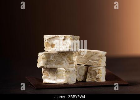 Kleine Nougat-Stücke auf dunklem Tisch Stockfoto