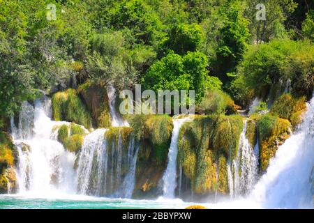 Ein malerischer Kaskadenwasserfall unter großen Steinen im Landschaftspark Krka, Kroatien im Frühjahr oder Sommer. Die besten großen, wunderschönen kroatischen Wasserfälle Stockfoto