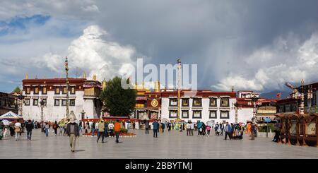 Panorama-Ansicht des Jokhang-Tempels mit bewölktem Himmel. Ein UNESCO-Welterbe und ein Zentrum des tibetischen buddhismus. Mit Pilgern und Besuchern. Stockfoto