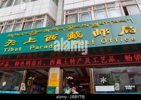 Auf dem Schild über dem Eingang des zentralen Postamtes in Lhasa steht "Tibet Paradise Post Office". Es ist in Englisch, Chinesisch und Tibetisch geschrieben. Stockfoto