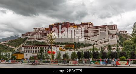 Panoramablick auf Potala Palace - ein UNESCO-Weltkulturerbe. Heimat des Dalai Lama. Alte Festung und Ziel für buddhistische Pilger. Blick auf die Straße Stockfoto