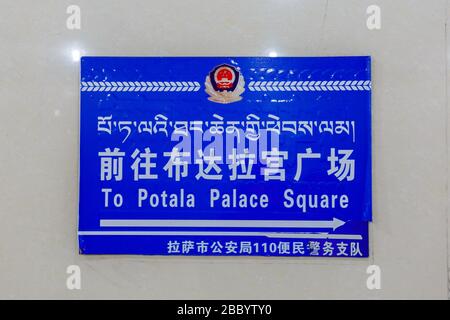 Blaues Schild in einer Unterführung, die den Weg zum berühmten Potala Palast weist. Das Zeichen ist dreisprachig: englisch, Mandarin und tibetisch. Stockfoto