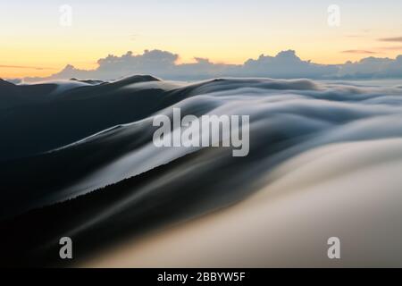 Erstaunlicher Morgennebel in den Bergen verschwommen von langer Belichtung. Landschaftsfotografie Stockfoto